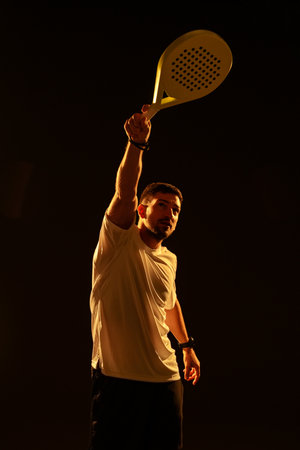 Player raises paddle in excitement during indoor sports competition, capturing the moment