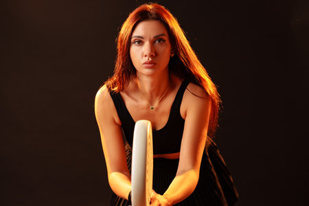 Woman poses with fitness hoop in a dark studio setting during a dynamic photoshoot session