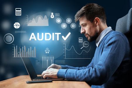 Man working on financial audit with digital graphs in a modern office settingの写真素材