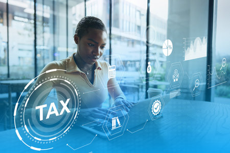 Expert working on tax calculations in a modern office setting during daylight hoursの写真素材