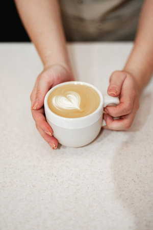 Barista serves latte with heart design at cozy coffee shop in the afternoonの写真素材