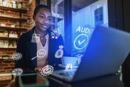 Young professional working on laptop with financial icons in a cozy cafe settingの写真素材