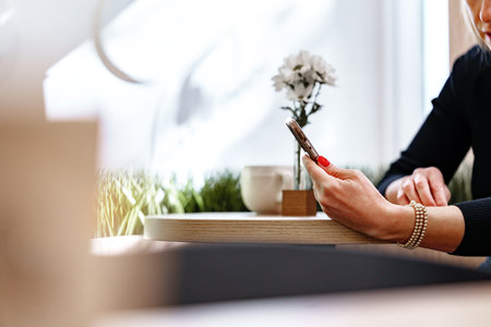 Woman enjoying coffee while browsing on her phone at a cozy cafe during the afternoonの写真素材