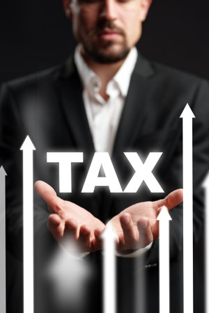 Businessman holds tax symbol, highlighting financial growth and fiscal responsibility in an officeの写真素材