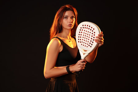 Female athlete poses confidently with a racket in a dramatic lighting setupの写真素材