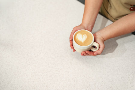 Barista creating latte art on freshly brewed coffee at a cafe during the morning hoursの写真素材