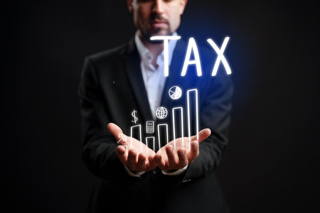Businessman holding graphs and tax symbols in a creative presentationの写真素材