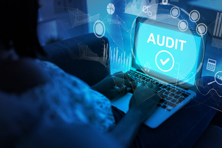 Person conducting a digital audit on a laptop in a darkened environment at nightの写真素材