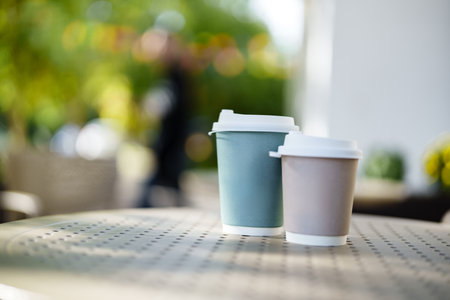 Coffee cups on a table in a sunny cafe garden during the afternoonの写真素材