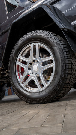 Close view of a shiny alloy wheel on a black SUV parked on a cobblestone street