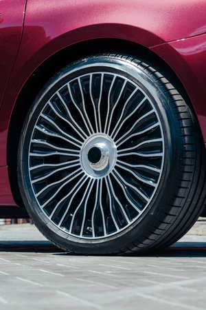 Stylish car wheel with intricate design parked on a sunny street
