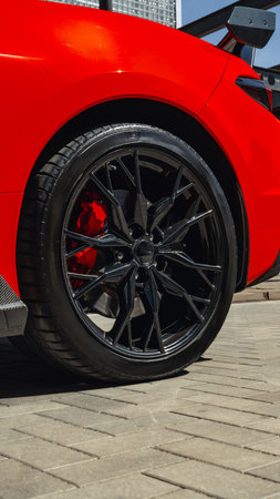 Bright red sports car showcasing sleek black rims in urban setting on sunny day