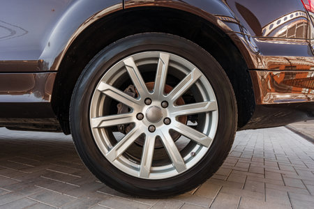 Close-up view of a stylish silver wheel on a car parked on a brick streetの写真素材