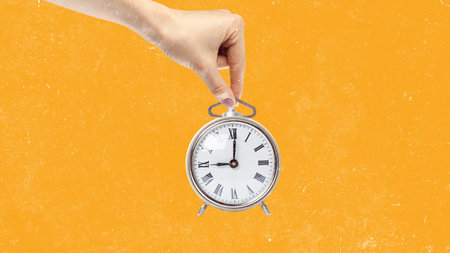 Hand holding vintage clock against bright orange background reminding of time management