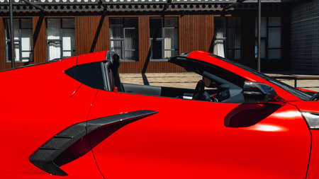Bright red sports car parked outside a modern building on a sunny dayの写真素材