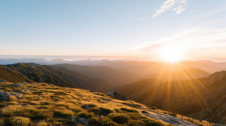Sunset view over mountains with soft light and grassy hills in the foregroundの素材