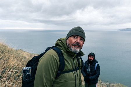 Explorers hiking near a coastal cliff during an overcast day in a remote location