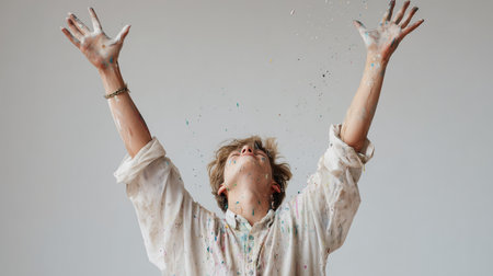 Young person celebrates with paint in indoor art studio setting during daylight hoursの素材