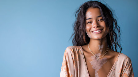 Woman smiles against blue wall while soap bubbles float around her in a light and cheerful momentの素材
