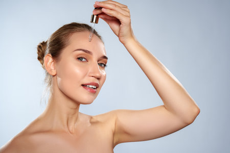 Woman applying skin serum in a bright setting during daytimeの写真素材