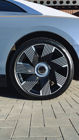 Modern car wheel with unique design displayed on paved surface near building