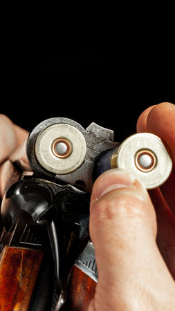 Hands hold a gun while preparing cartridges for a shooting activity indoorsの写真素材
