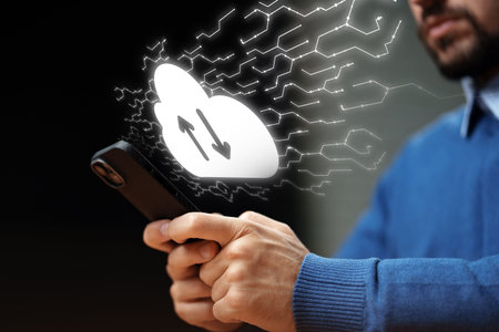 Person using smartphone to upload data to a cloud service in a dark setting