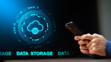 Person holds smartphone while looking at cloud data storage graphic on a screenの写真素材