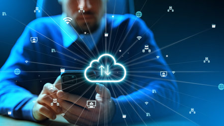 Man using smartphone to access cloud services at a workspace during evening hours