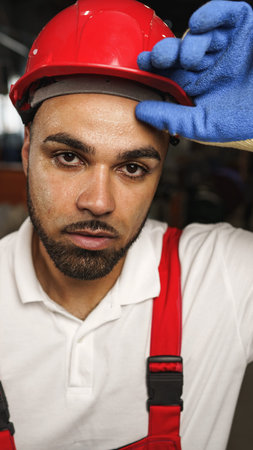 Worker shows determination and focus while wearing safety gear in a workshop settingの写真素材