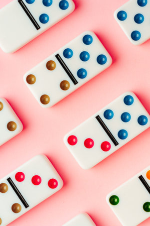 Colorful dominoes arranged on a pink surface with different dot patterns