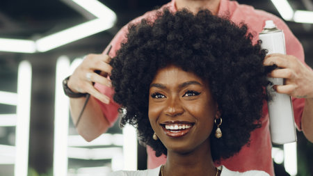 Hair styling session with a client smiling in a salon during daylight hoursの写真素材