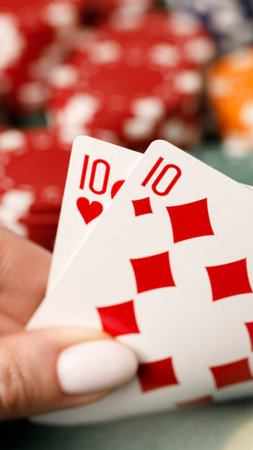 Holding two ten cards in a poker game with red chips on the table during a casino night