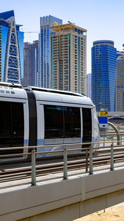Train moves through city near tall buildings on a sunny day in Dubaiの写真素材