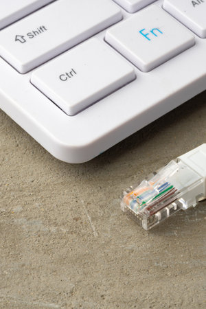 Close-up of a keyboard and an ethernet cable connection on a concrete surface