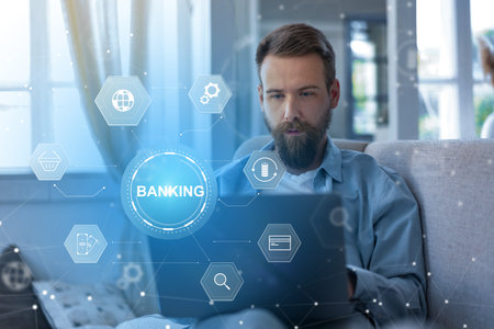 Man uses laptop at home for banking invoice payment in modern living roomの写真素材