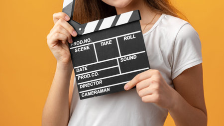 Woman holds a movie clapperboard on an orange background for a film scene