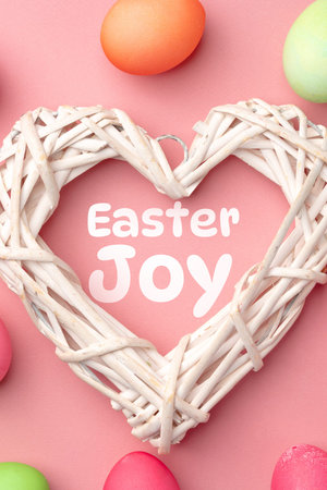 Easter joy is celebrated with colorful eggs and a heart-shaped decoration on a pink background
