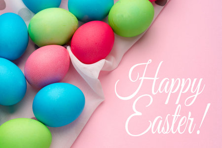 Colorful Easter eggs on pink background with cheerful message for holiday celebration