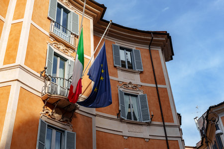 Italian flag and European Union flag wave from building balcony in Rome