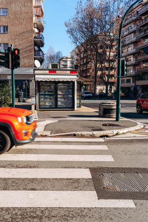 Traffic flows past a closed vendor stand on a city street in the afternoon light