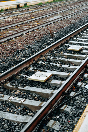 Tracks are seen with gravel and wooden ties in a railway yard during a rainy day
