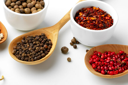 Many spices displayed in bowls and on wooden spoons for cooking and seasoning food