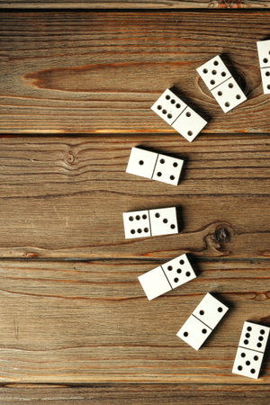 People play a game with white dominoes on a wooden table in the afternoon