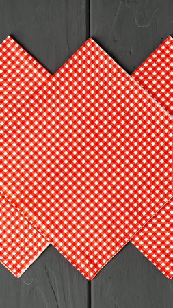 Checkered tablecloth in red and white pattern placed on a dark table