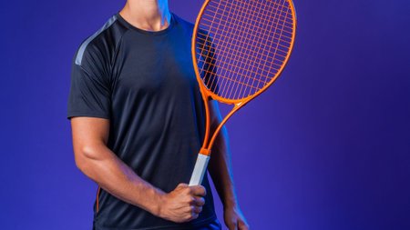 Tennis player poses with racket against a purple background in a studio settingの写真素材