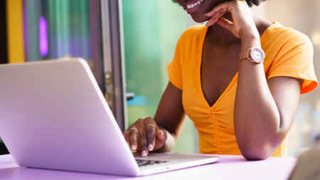 Woman using laptop with smile at a bright cafe during the afternoonの写真素材