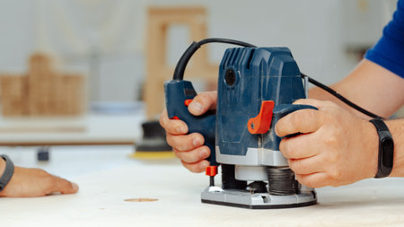Worker uses router on wood in workshop during daytime to craft a project