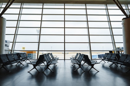 Waiting area at an airport with many empty chairs and a view outsideの写真素材
