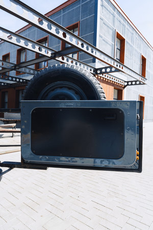 Black storage compartment attached to a trailer near a building on a sunny day